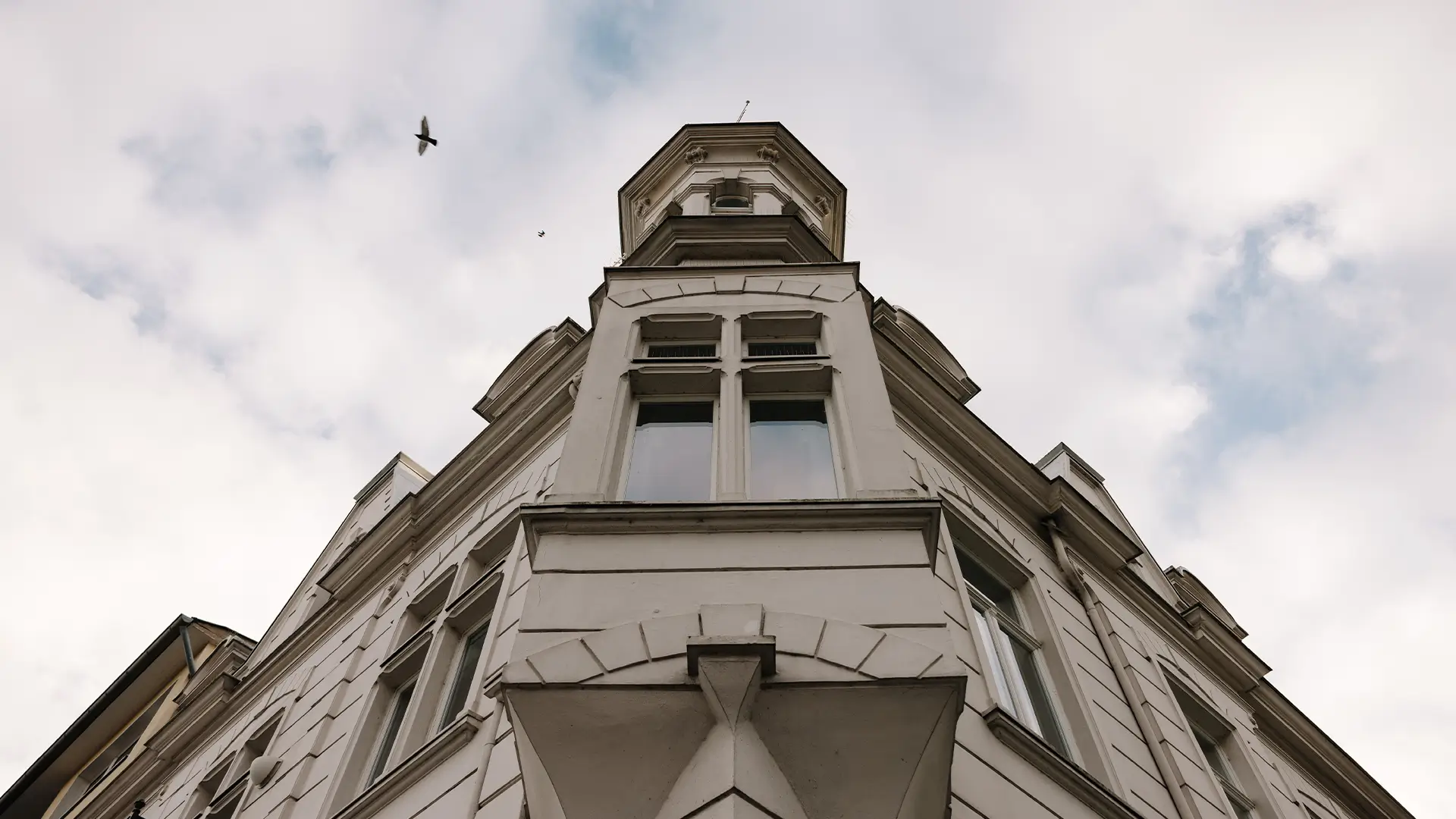 Historisches Kanzleigebäude der Kanzlei Schwarz mit heller Fassade und markantem Eckturm, aus der Froschperspektive fotografiert.