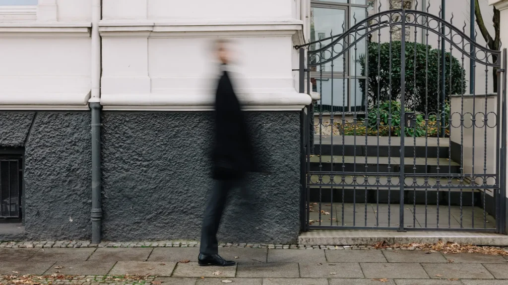 Person in dunkler Kleidung geht an der Fassade eines historischen Gebäudes vorbei.